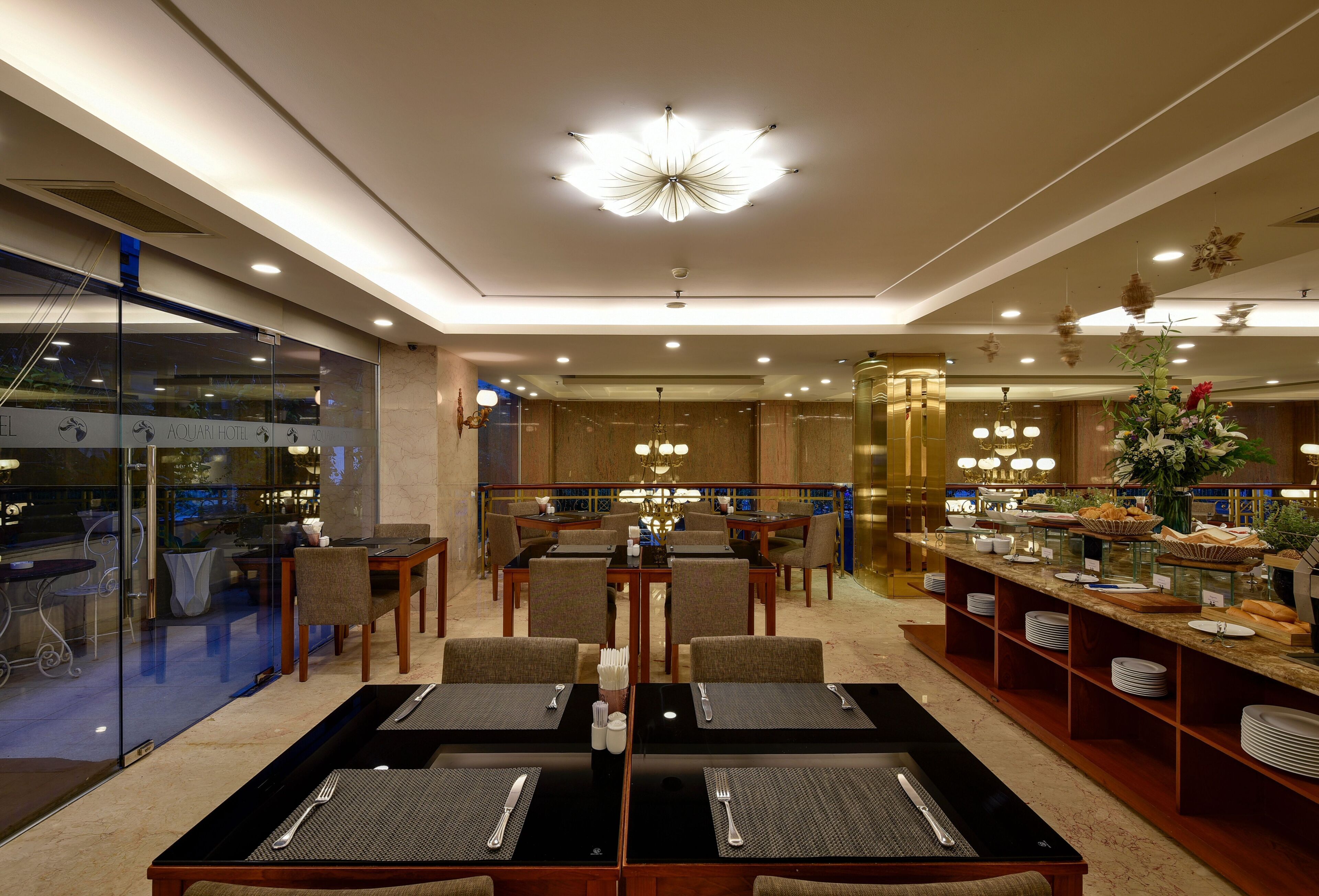 A hotel lobby with a central dining area, seating arrangements, and a buffet.