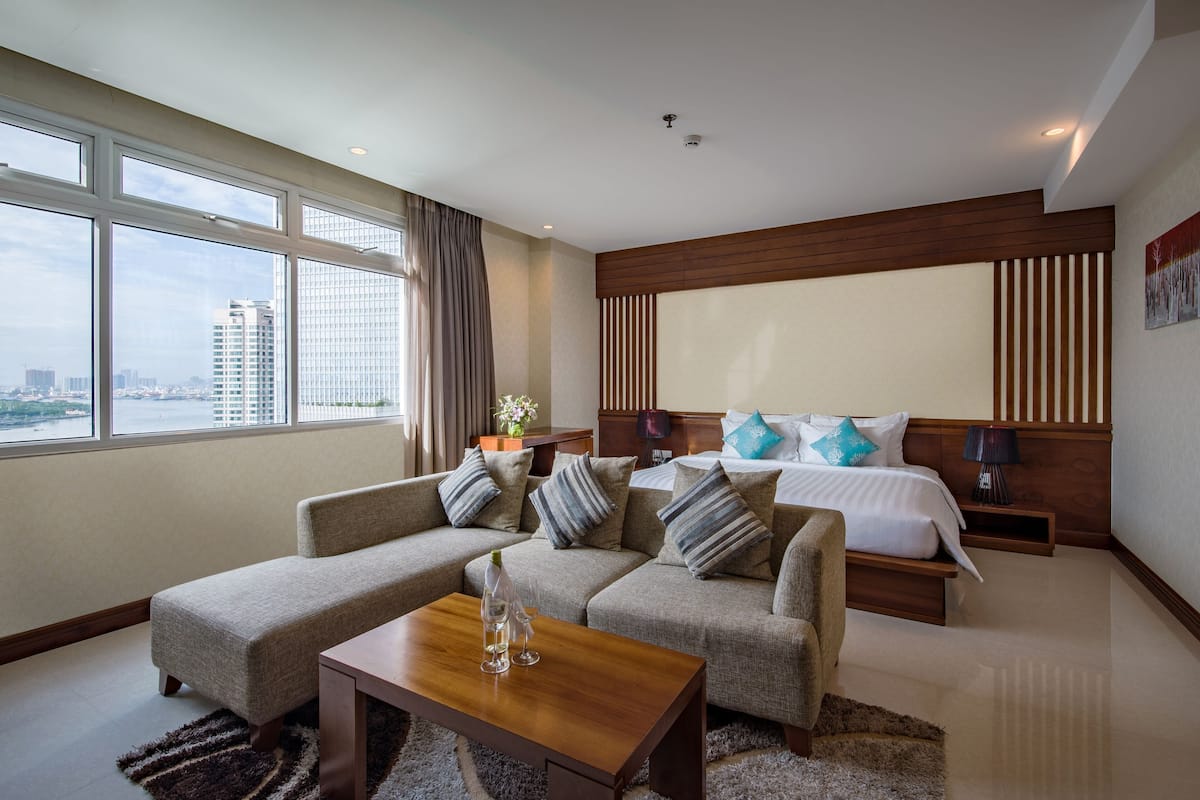 A modern hotel room with a large bed, a sofa, and a view of the city.