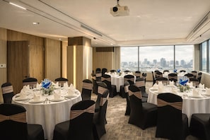 A conference room with round tables, black chairs, and a city view.
