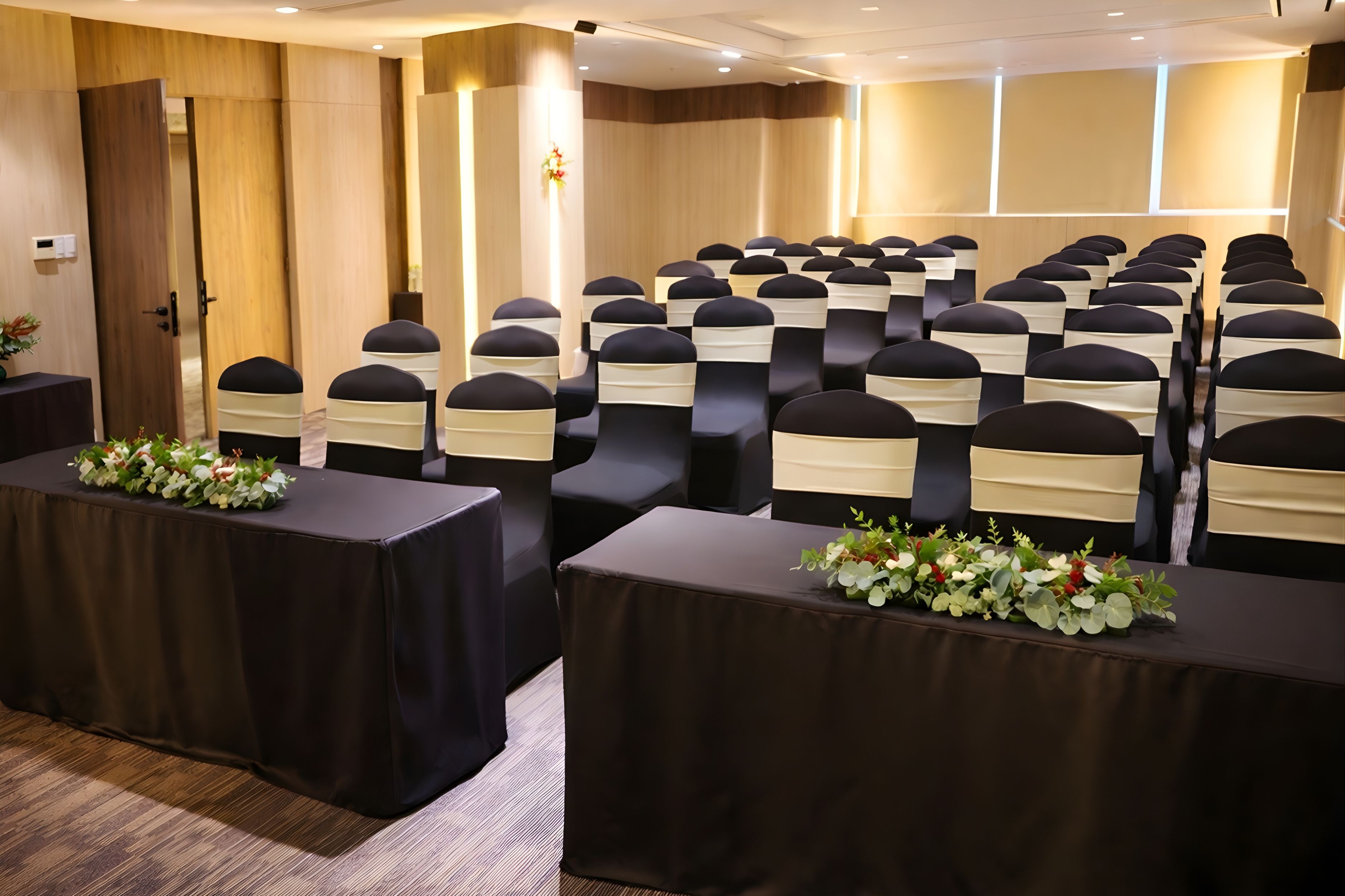 A conference room with rows of chairs, tables, and floral centerpieces.