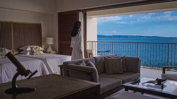 A hotel room with two beds, a sofa, a coffee table, and a view of the sea.