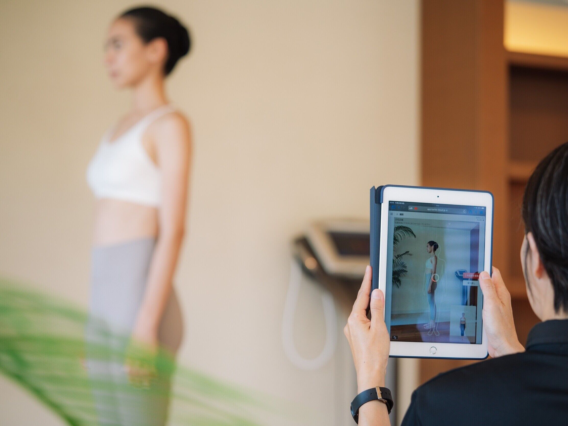 Une personne utilise une tablette pour prendre une photo d’une autre personne qui se tient devant un miroir.
