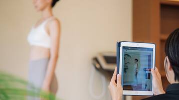 Une personne utilise une tablette pour prendre une photo d’une autre personne qui se tient devant un miroir.