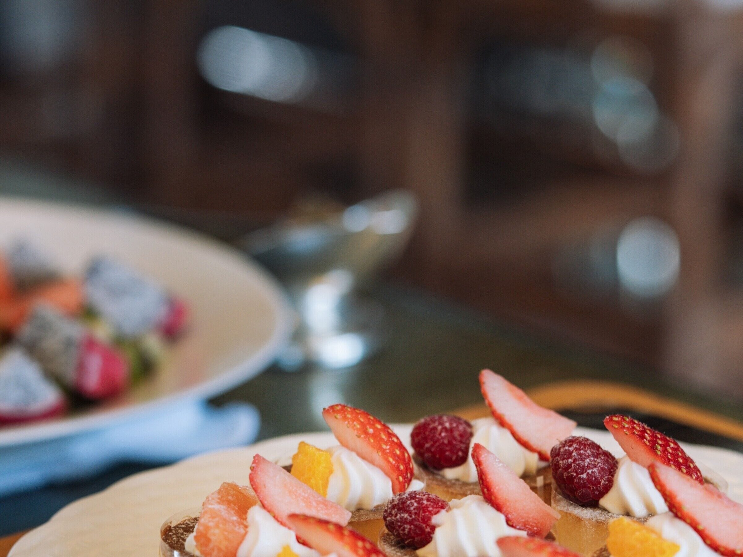 Un postre con fresas, frambuesas y rodajas de naranja sobre un plato.