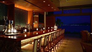A bar area with a long counter, multiple chairs, and a view of the night sky. - The Terrace Club Wellness Thalasso At Busena (Nago)
