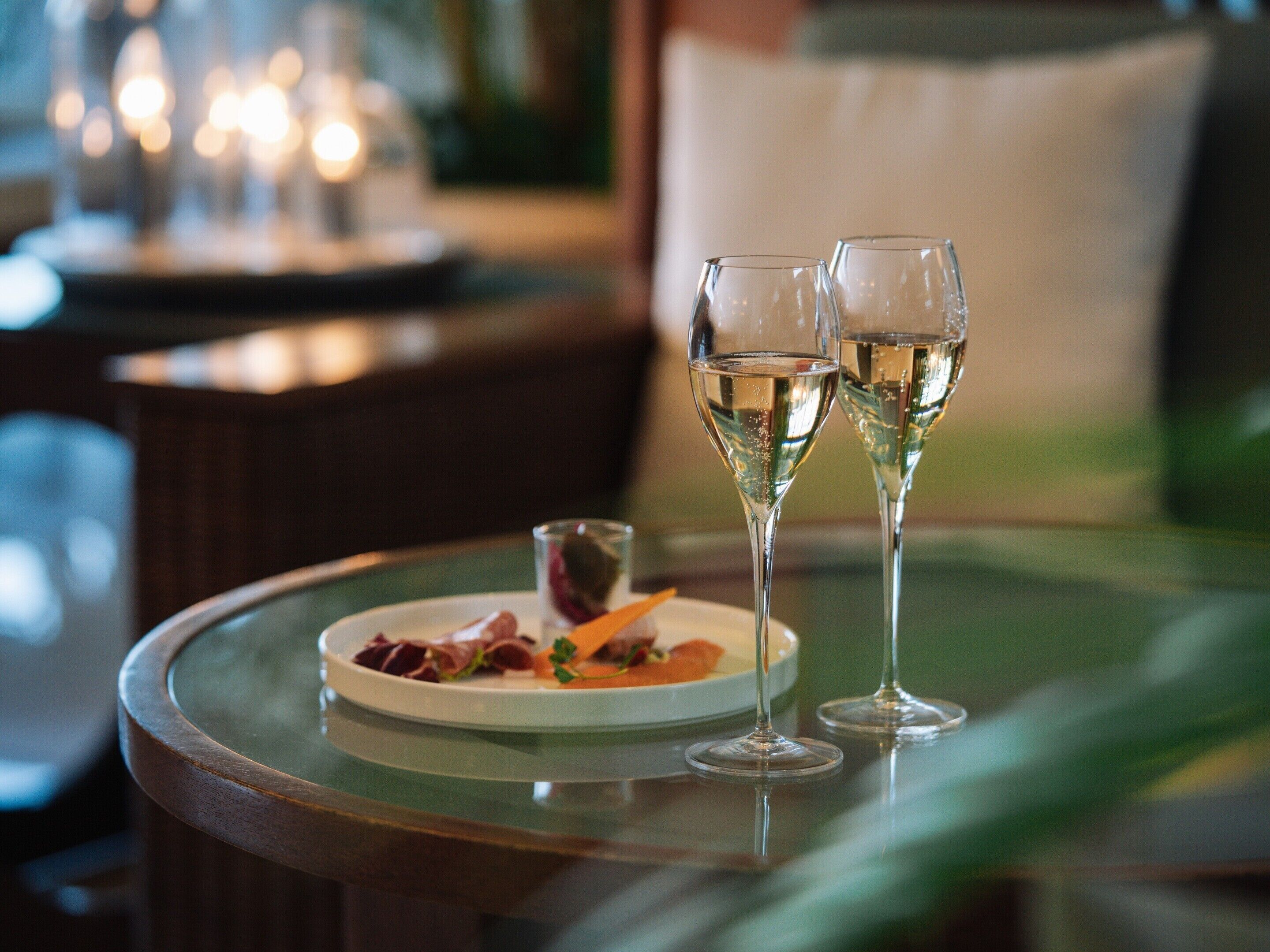 A dining table with two wine glasses and a plate of food.
