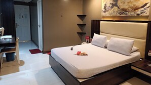 Una habitación de hotel moderna con una cama grande, un escritorio con una silla, una mesita y un cuadro en la pared.