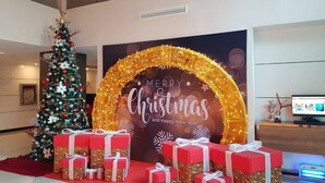 Un espacio interior decorado con un árbol de Navidad, un cartel que dice 'Merry Christmas and Happy New Year' y varias cajas de regalo.