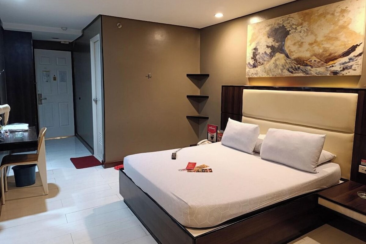 Una habitación de hotel con una cama, mesitas de noche, un escritorio y una silla.