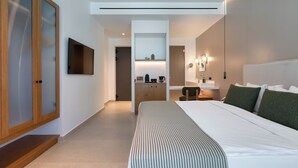 Une chambre d’hôtel moderne équipée d’un grand lit, d’une télévision, d’une kitchenette et d’une salle de bain.