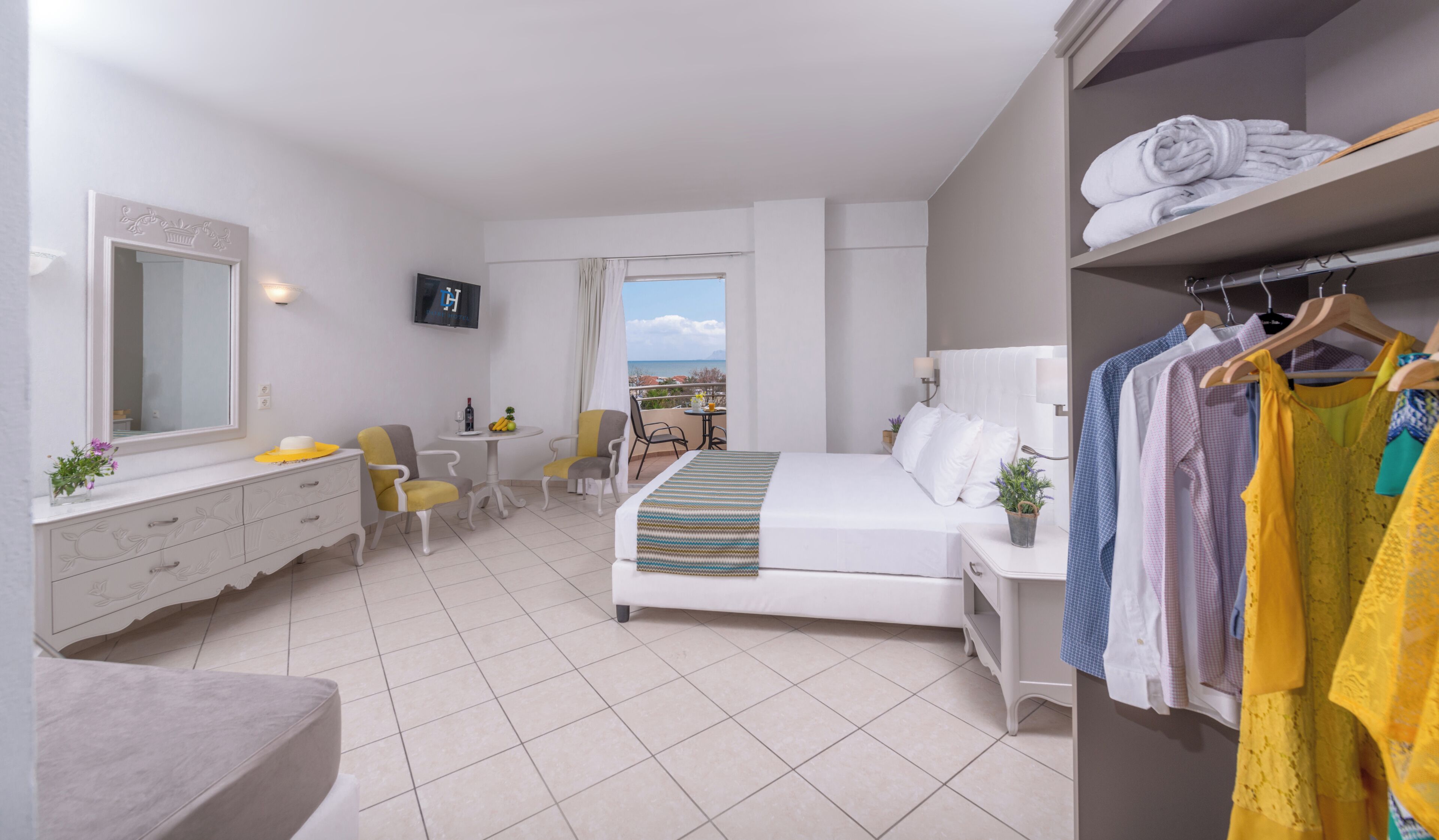 A hotel room with a bed, a desk, a chair, a wardrobe, and a balcony with a view.
