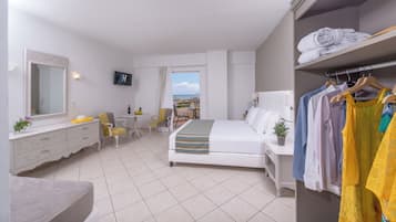 Habitación de hotel con cama, escritorio, silla, armario y balcón con vistas.