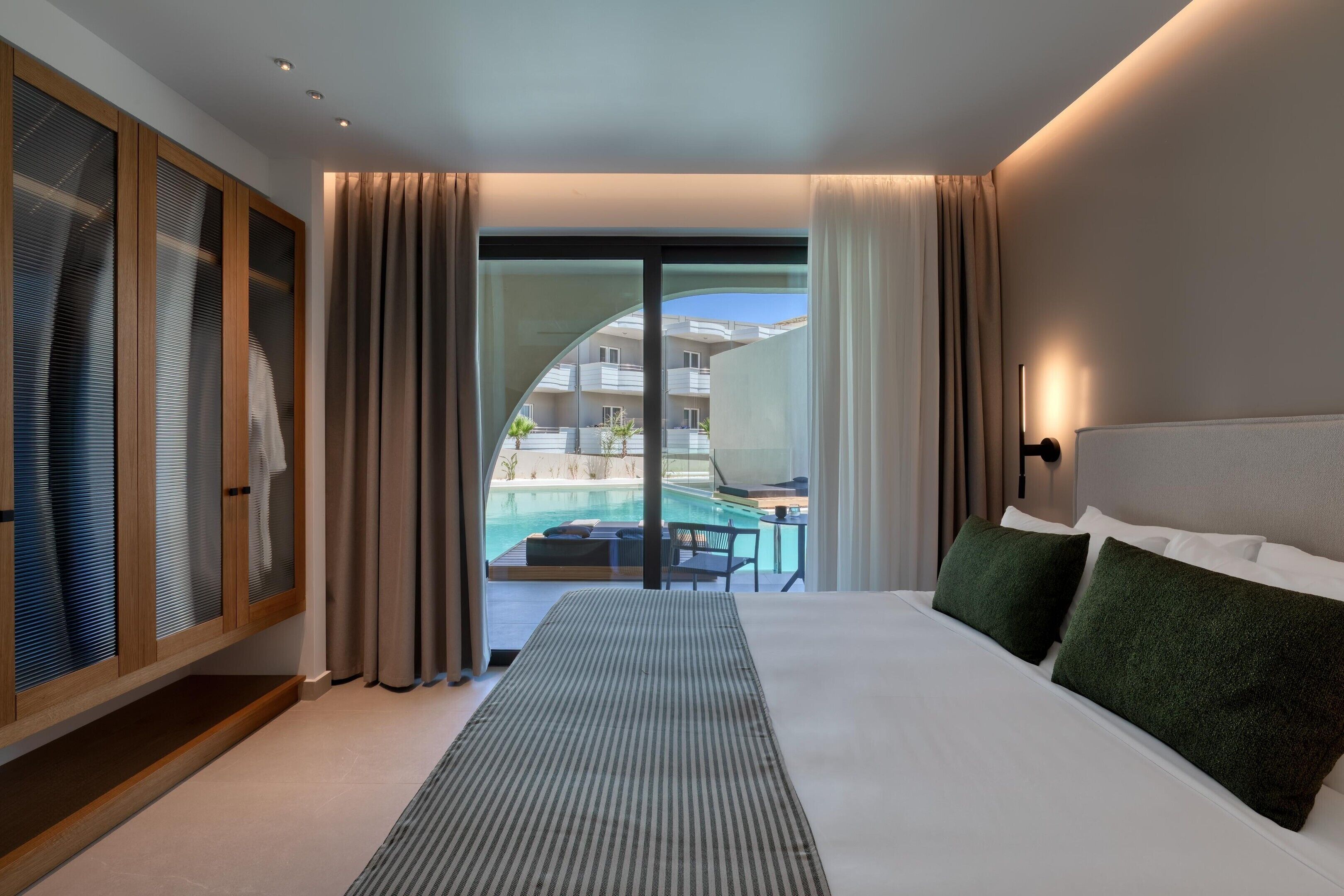 Ein Hotelzimmer mit Bett, Blick auf einen Pool und einer Schiebetür.