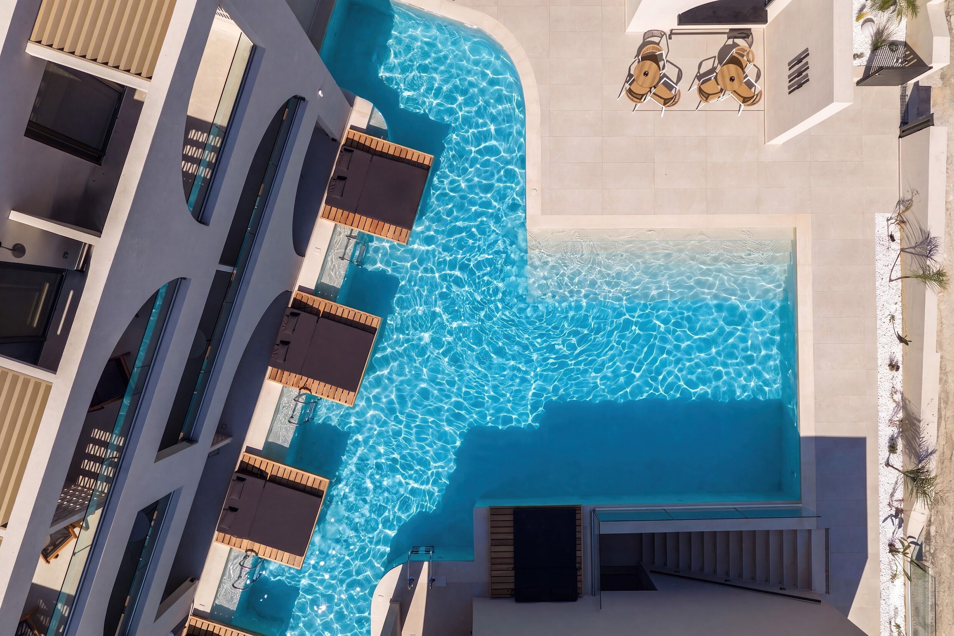 Vista aérea de un hotel con piscina, varios balcones y zonas de estar al aire libre.