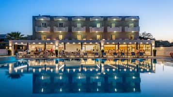 Un hotel con piscina, varios balcones y zonas de estar al aire libre.