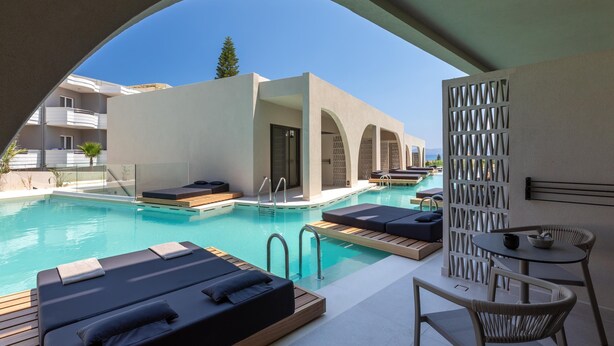 A pool area with lounge chairs, a table, and a view of the pool. - Dore Hotel (Chania)