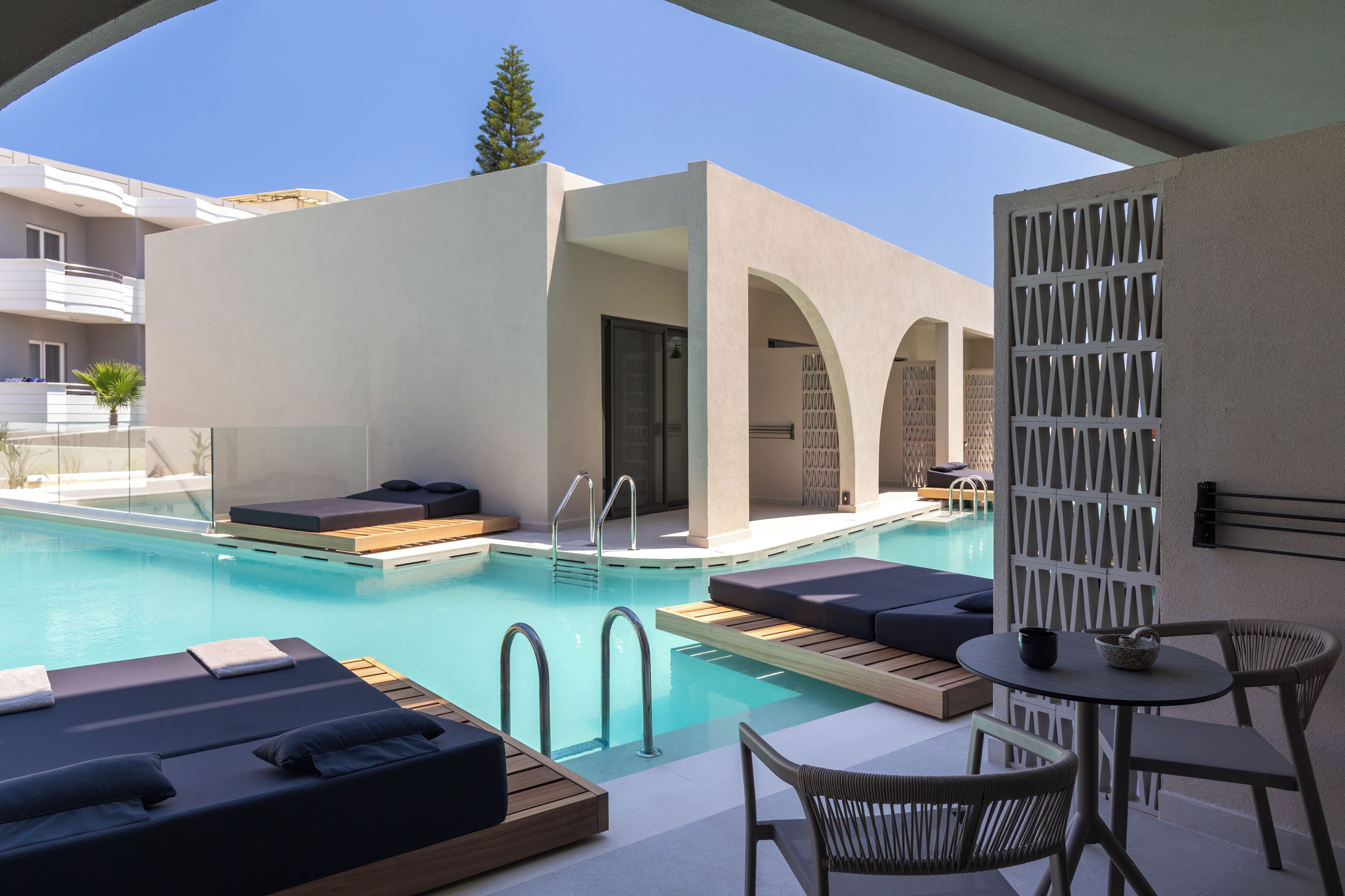 A modern pool area with lounge chairs, a small table, and a pool ladder.