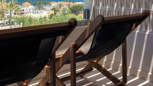 A balcony with a view of the sea, a white wall with a geometric pattern, and two black chairs. - Dore Hotel (Chania)