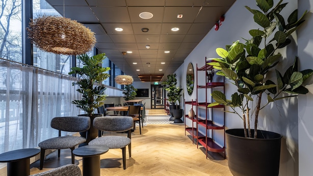 A modern interior with seating areas, large windows, and indoor plants. - Scandic Postitalo (Tampere)