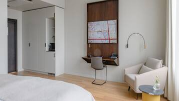 Una habitación de hotel moderna con una cama, un escritorio con una silla, un sofá y un mapa en la pared.