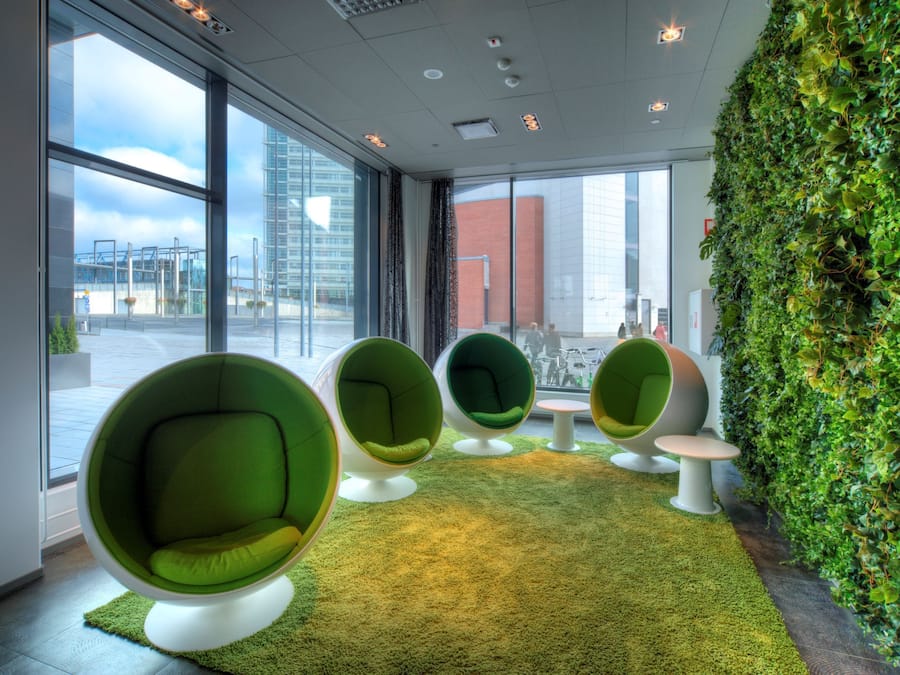 A modern interior with large windows, green chairs, and a green wall.