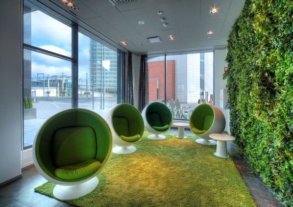 Un interior moderno con ventanas amplias, sillas verdes y una pared verde.