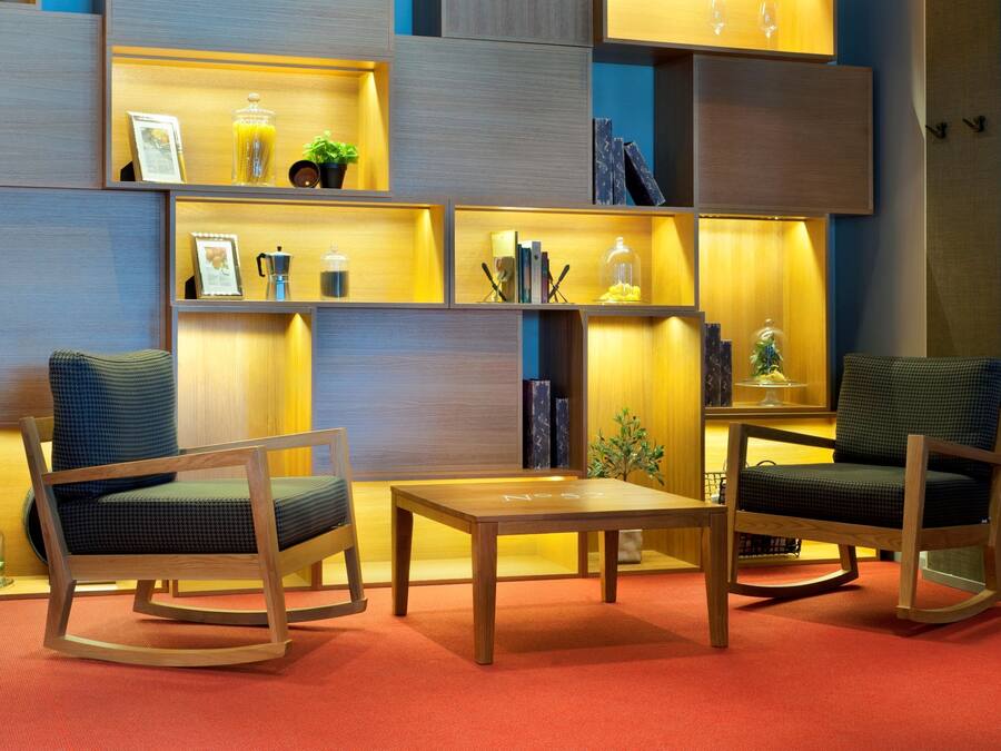 Un salon moderne avec des meubles en bois, dont deux fauteuils à bascule et une petite table. On peut voir des étagères ornées d’objets décoratifs et de livres.
