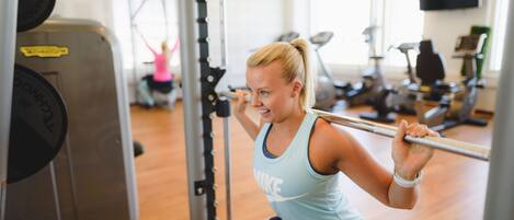 A gym with exercise equipment, including a squat rack and a bench.