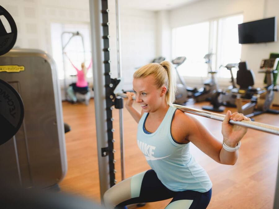A gym with exercise equipment, including a squat rack and a bench.
