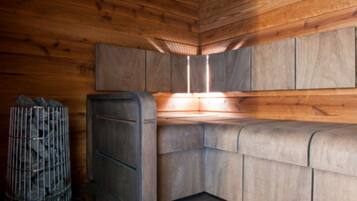 A corner of a wooden cabin with a metal cabinet and a metal cage.