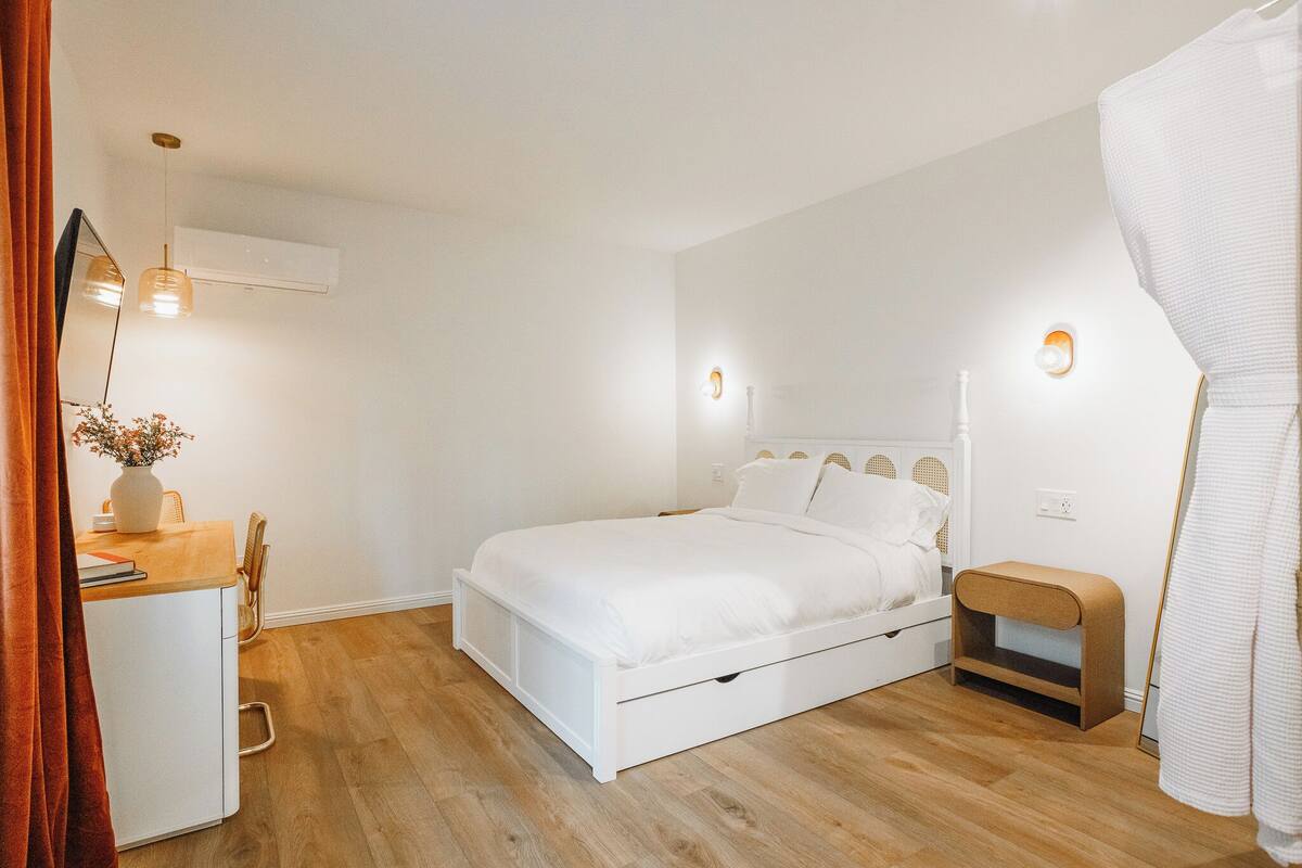 A bedroom with a bed, bedside table, and a desk with a chair.