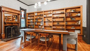 A cozy library with wooden bookshelves, a fireplace, and a dining area with chairs. - Kaleidoscope Inn & Gardens (Nipomo)