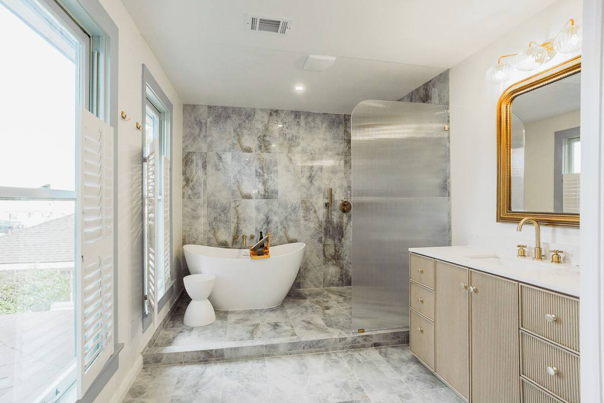 A modern bathroom with a freestanding bathtub, a walk-in shower, and a vanity with a large mirror.