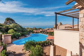 Ein Pool mit Meerblick, umgeben von Liegestühlen und einem Steinhaus.
