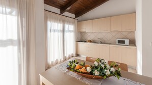 Une cuisine avec des meubles en bois, un four à micro-ondes et un coin repas avec une table mise pour deux personnes.