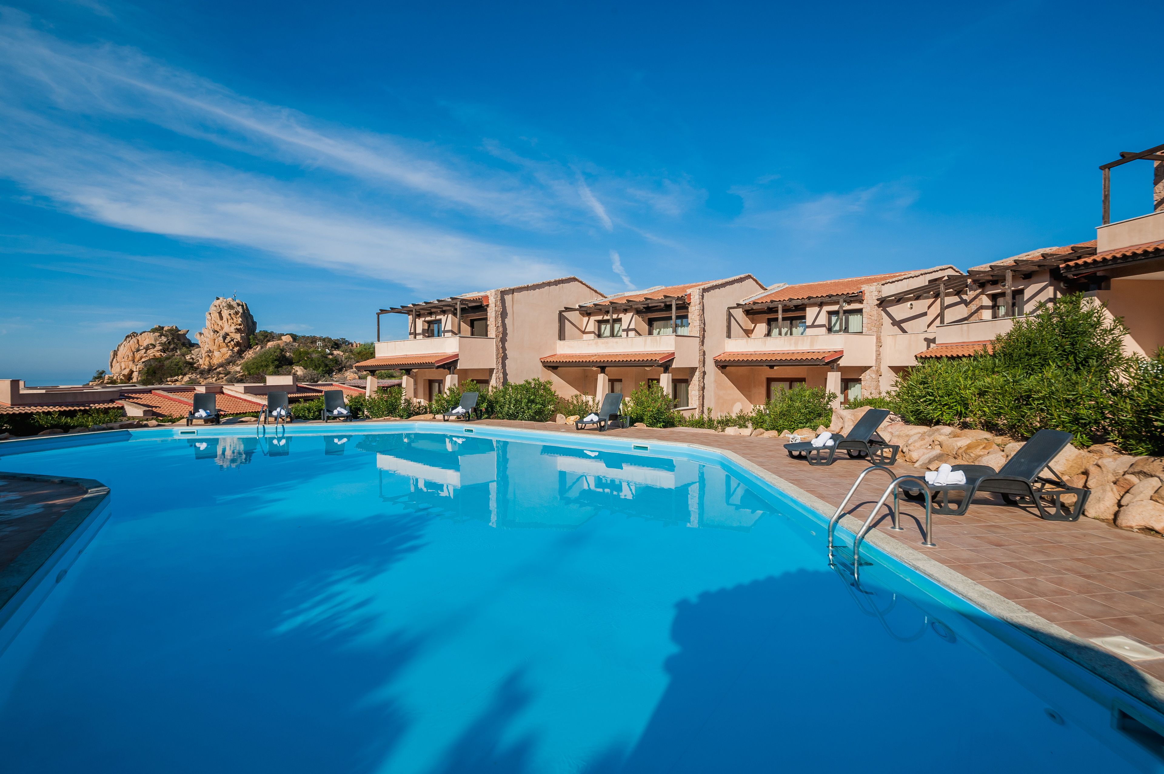 A swimming pool with lounge chairs and a building with balconies.