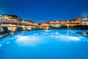 Ein Pool mit Liegestühlen und ein Gebäude im Hintergrund mit mehreren Balkonen.
