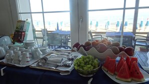 Un buffet de petit-déjeuner avec des assiettes, des couverts et des fruits, comme des raisins et des tranches de pastèque.
