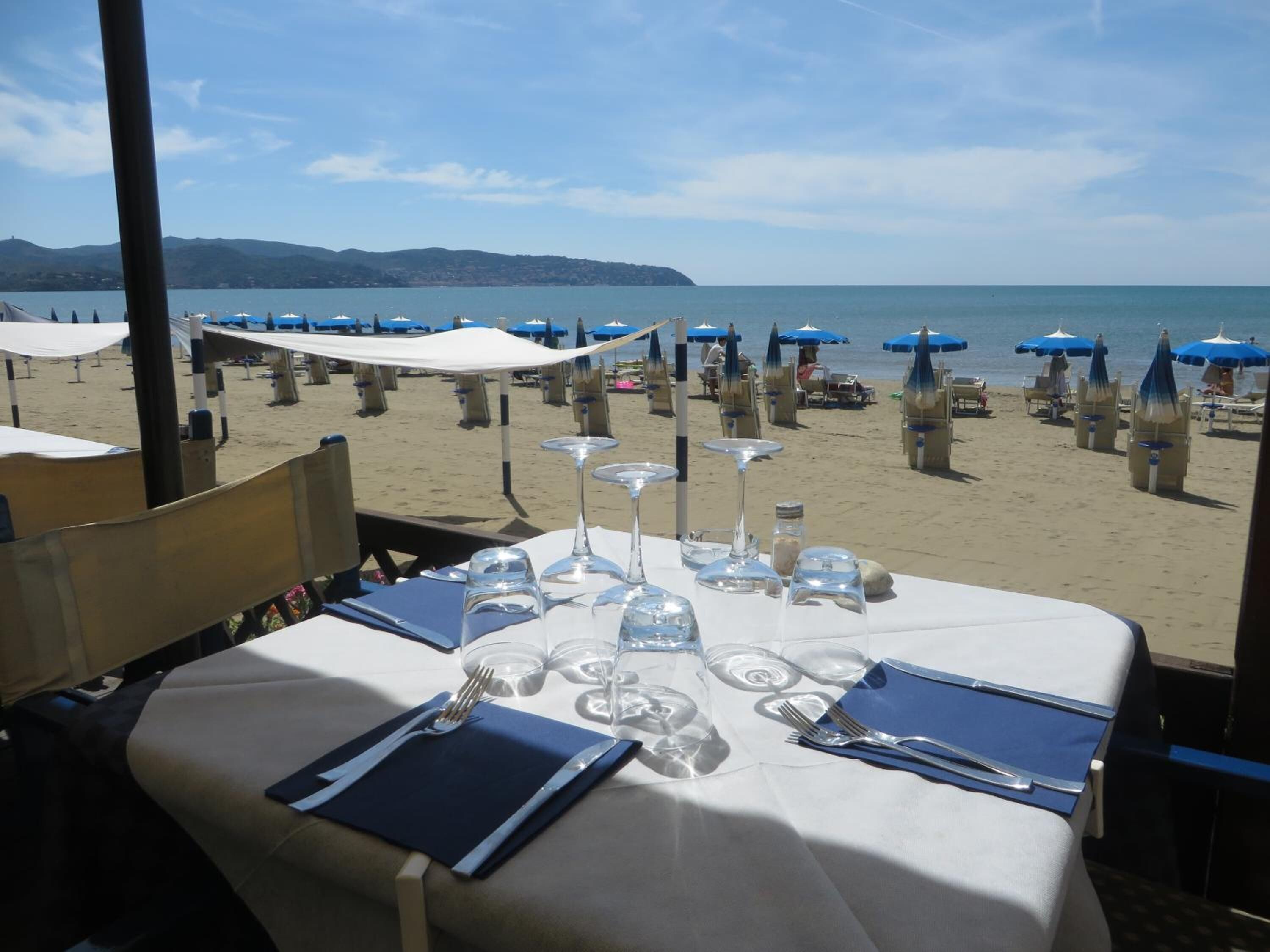 Tavola imbandita per cena con vista sulla spiaggia e sull'oceano.