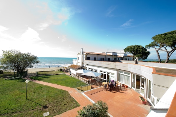 Una propiedad costera con patio, vista al mar y un gran árbol.