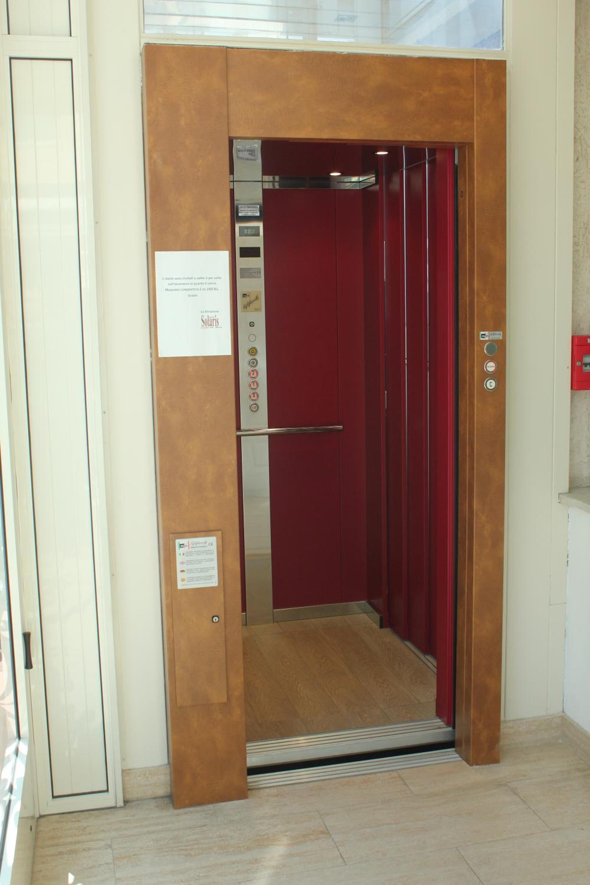 An elevator with a red interior and a metallic door handle.