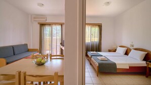 A hotel room with a bed, a sofa, a dining table with chairs, and a window with curtains.