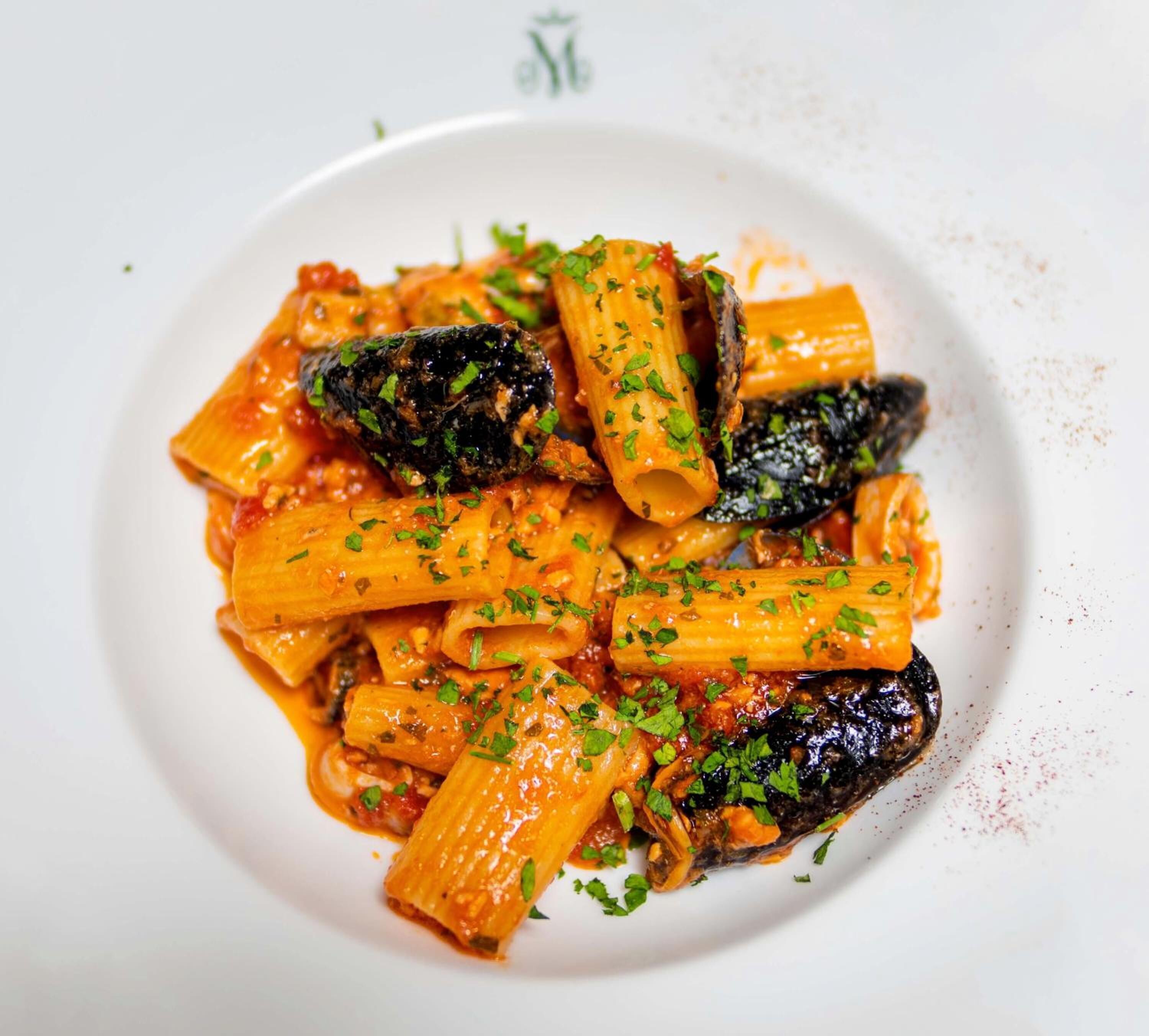 Un plato de pasta con salsa de tomate y champiñones, adornado con hierbas picadas.