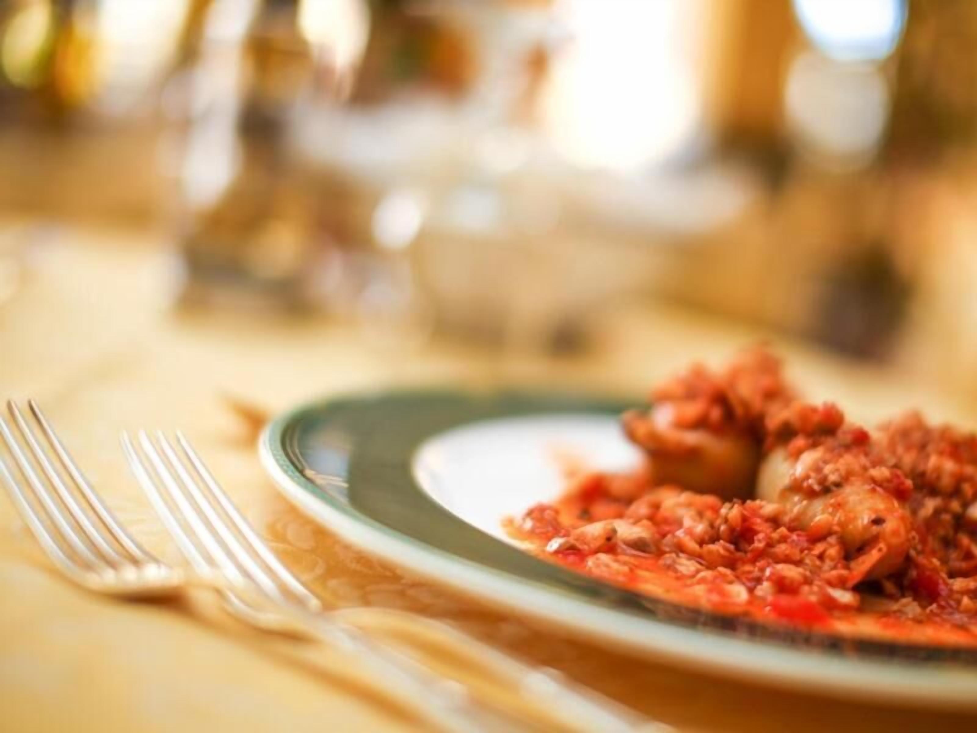 A plate of food on a table with a fork and spoon beside it.