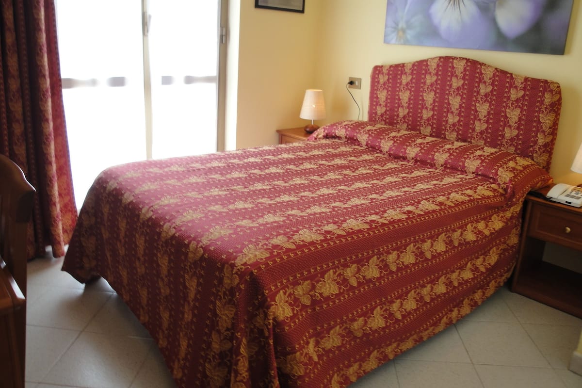 Une chambre à coucher avec un lit, une table de chevet, une lampe et un tableau au mur.