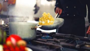 A kitchen with a pot on the stove and a person cooking.