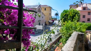 A balcony with purple bougainvillea flowers, a street view with buildings, and a clear blue sky. - Hotel Miranda (Varazze)