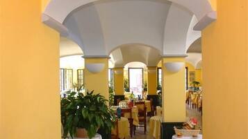 A restaurant with yellow walls, white ceiling arches, and tables set for dining.