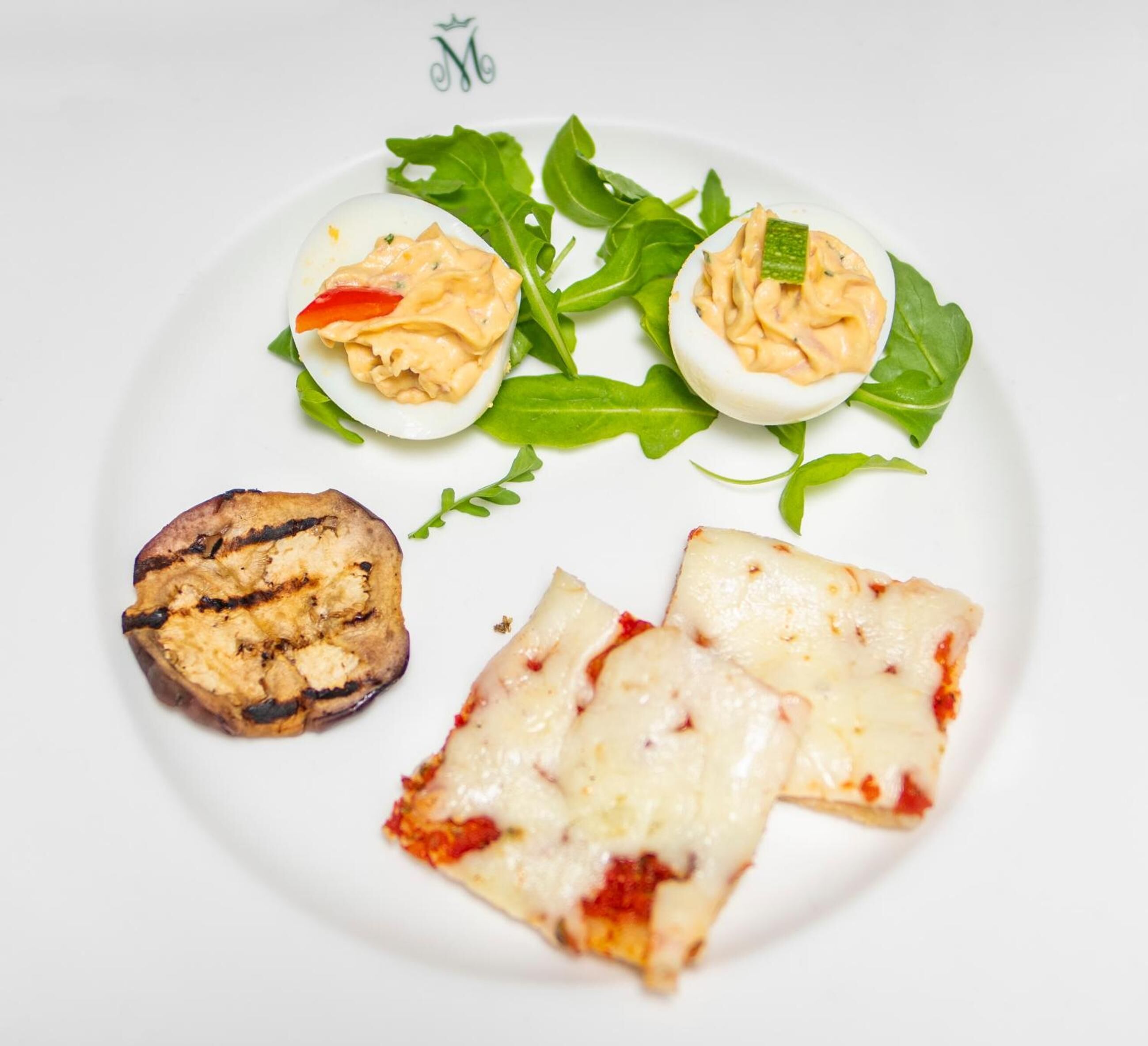 A plate with deviled eggs, grilled mushroom, and cheese slices.