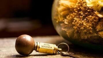 Un llavero con un tirador de madera y un anillor, acostado junto a una llave, con un fondo desenfocado.